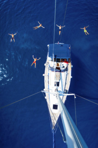 Shot of the sailing boat with a swimmers in the sea. Taken from the top of the mast. 